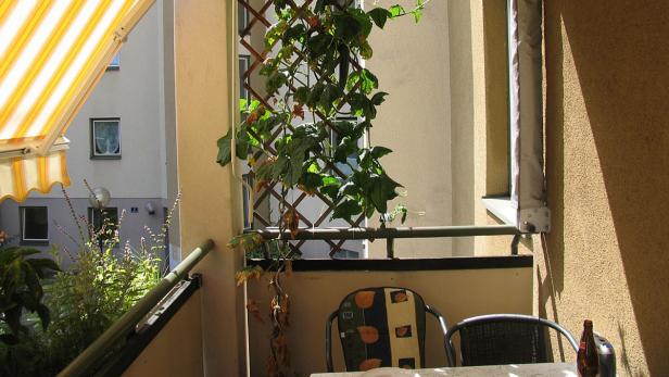 Ein sonniger Balkon mit Pflanzen, Stühlen und einem Tisch.