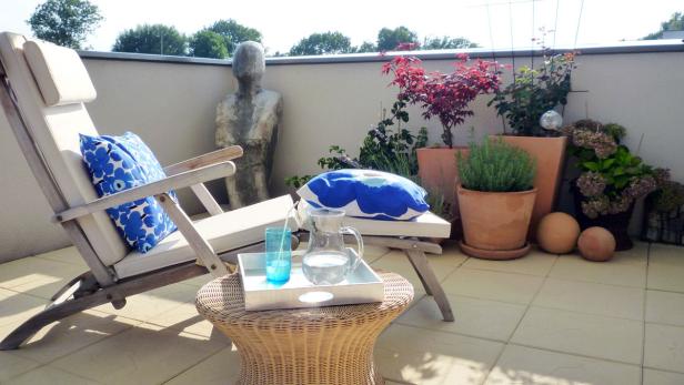 Ein Liegestuhl und Pflanzen auf einer sonnigen Terrasse.