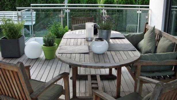 Ein Holztisch und Stühle stehen auf einer Terrasse mit Pflanzen.