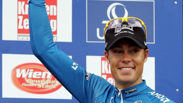 Tom Danielson wurde nach seinem Doping-Geständnis der Sieg bei der Ö-Tour aberkannt. Ein Radrennfahrer in blauem Trikot und Kappe mit erhobenem Arm lächelt.