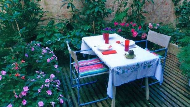 Ein gedeckter Tisch mit Geschirr in einem üppigen Garten.