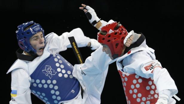 Zwei Taekwondo-Kämpfer im Wettkampf, einer mit blauem, der andere mit rotem Kopfschutz.