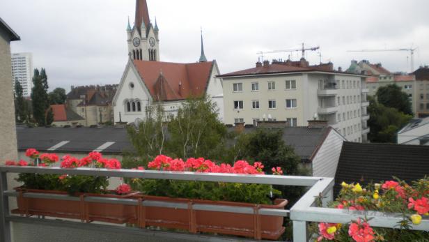 Blick von einem Balkon auf eine Stadtlandschaft mit Kirche und Wohnhäusern.