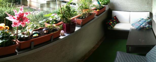 Ein Balkon mit Blumenkästen, einem Windrad und einer Sitzecke.