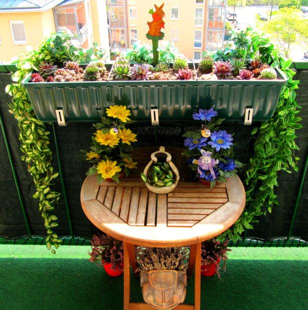 Ein kleiner Tisch mit Blumen und Dekorationen auf einem Balkon.