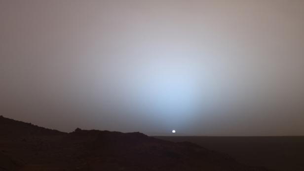 Ein blasser Sonnenuntergang über der staubigen Landschaft des Mars.