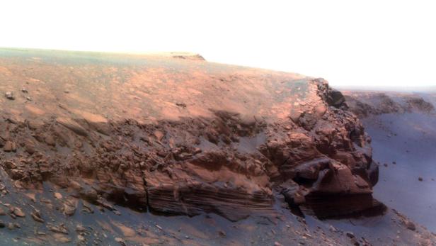 Eine Landschaft auf dem Mars mit roten Felsen und sandigem Boden.