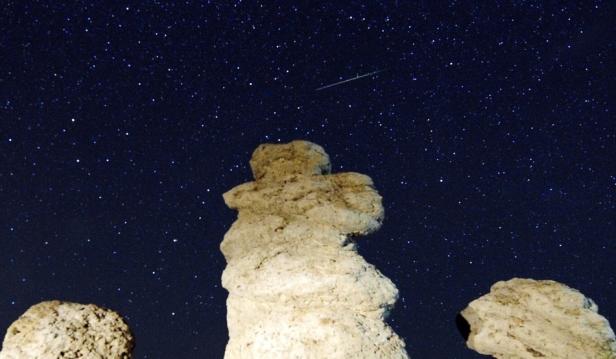 Sternenhimmel mit Sternschnuppe über Kalksteinformationen.