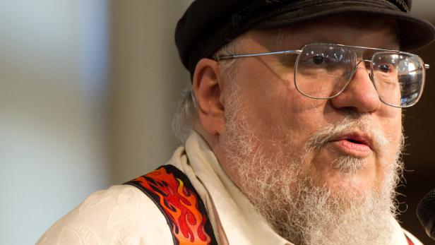 George R.R. Martin mit Bart, Brille und Mütze spricht in ein Mikrofon.