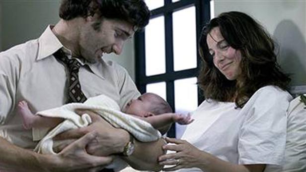 Ein Mann und eine Frau betrachten liebevoll ein Baby, das in eine Decke gewickelt ist.