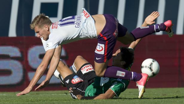 Zwei Fußballspieler kämpfen um den Ball auf dem Spielfeld.