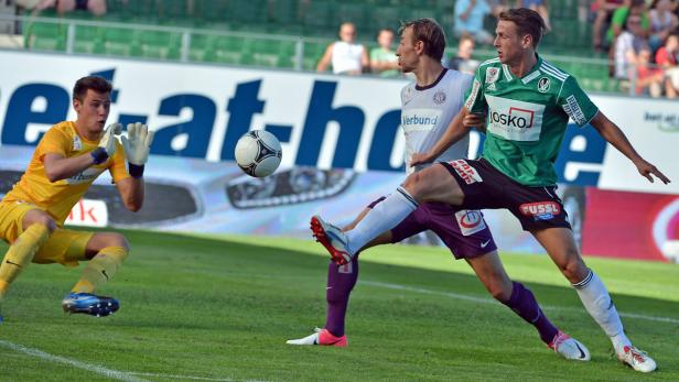 Ein Fußballspieler schießt den Ball, während der Torwart sich bereit macht, ihn zu fangen.