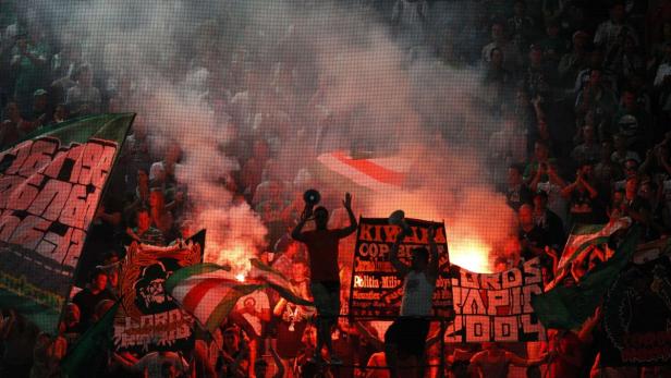 Fußballfans zünden Bengalos und schwenken Fahnen im Stadion.