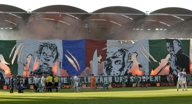 Ein Fußballspiel mit einem großen Banner, das Horrorfilmfiguren zeigt.