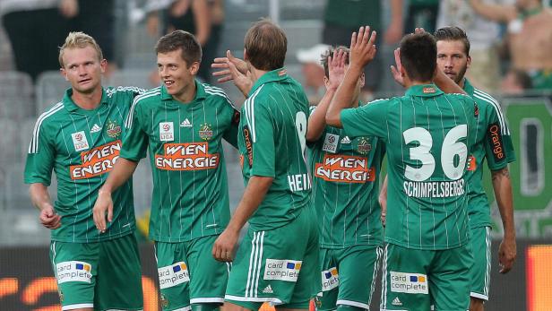 Mehrere Fußballspieler von Rapid Wien feiern gemeinsam auf dem Spielfeld.
