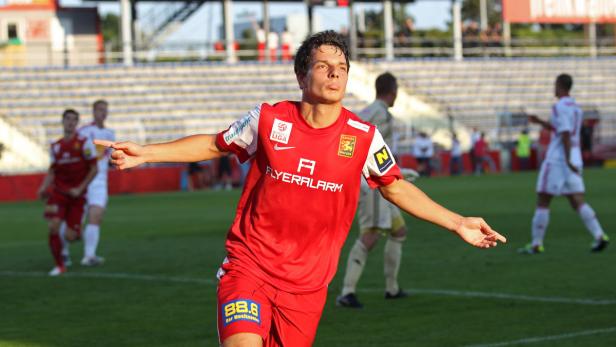 Ein Fußballspieler in roter Spielkleidung jubelt auf dem Spielfeld.
