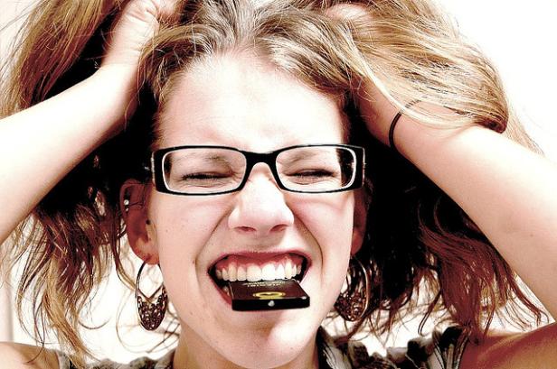 Eine gestresste Frau mit Brille hält eine Speicherkarte im Mund und rauft sich die Haare.