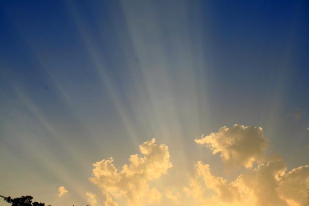 Sonnenstrahlen scheinen durch den blauen Himmel und beleuchten die Wolken.