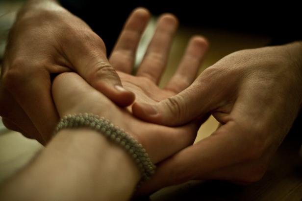 Eine Hand hält sanft die Hand einer anderen Person, die ein Armband trägt.