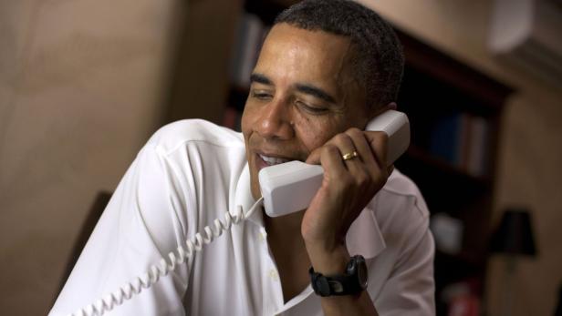 Barack Obama telefoniert mit einem weißen Festnetztelefon.