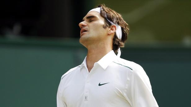 Roger Federer mit weißem Stirnband und Polohemd blickt nach oben.