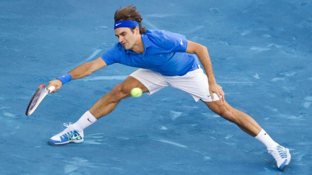 Roger Federer spielt einen Vorhandschlag auf einem blauen Tennisplatz.