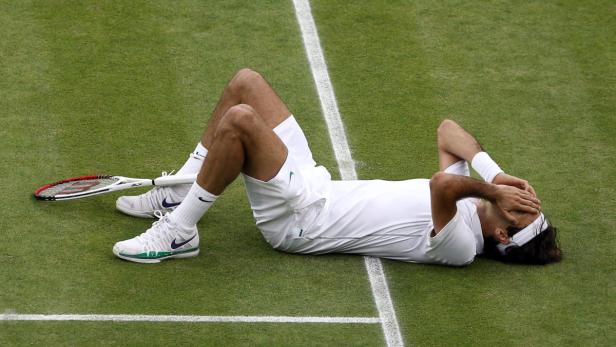 Ein Tennisspieler liegt enttäuscht auf dem Rasenplatz.