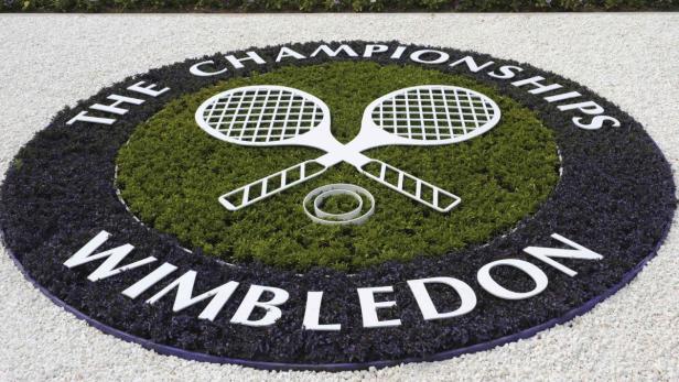Das Wimbledon-Logo mit gekreuzten Tennisschlägern auf einem Blumenbeet.