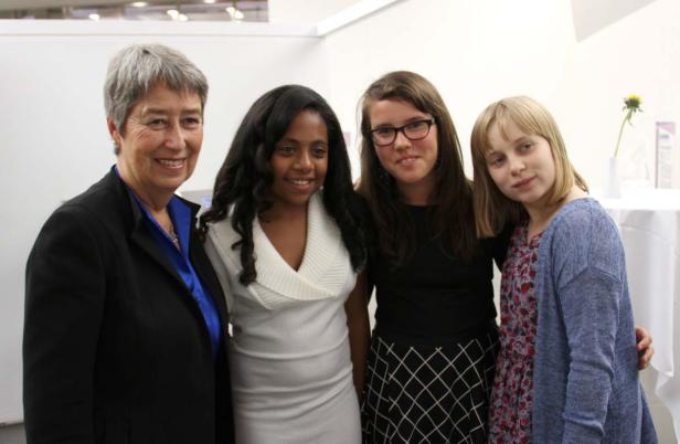 Vier Frauen unterschiedlichen Alters stehen nebeneinander und lächeln.
