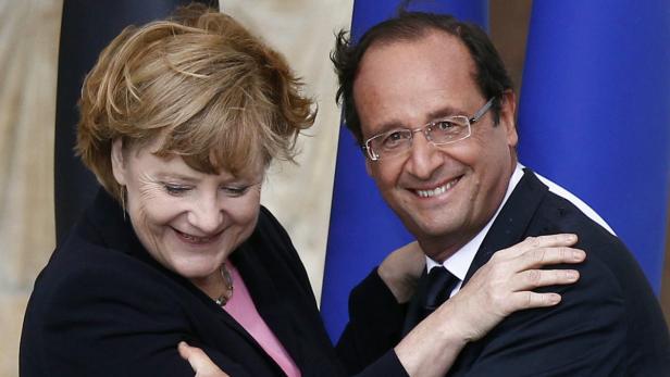 Angela Merkel und François Hollande umarmen sich lächelnd.
