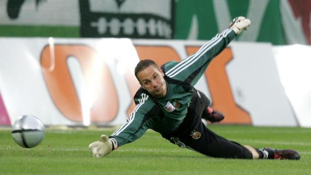 Ein Fußballtorwart hechtet nach einem Ball auf dem Spielfeld.