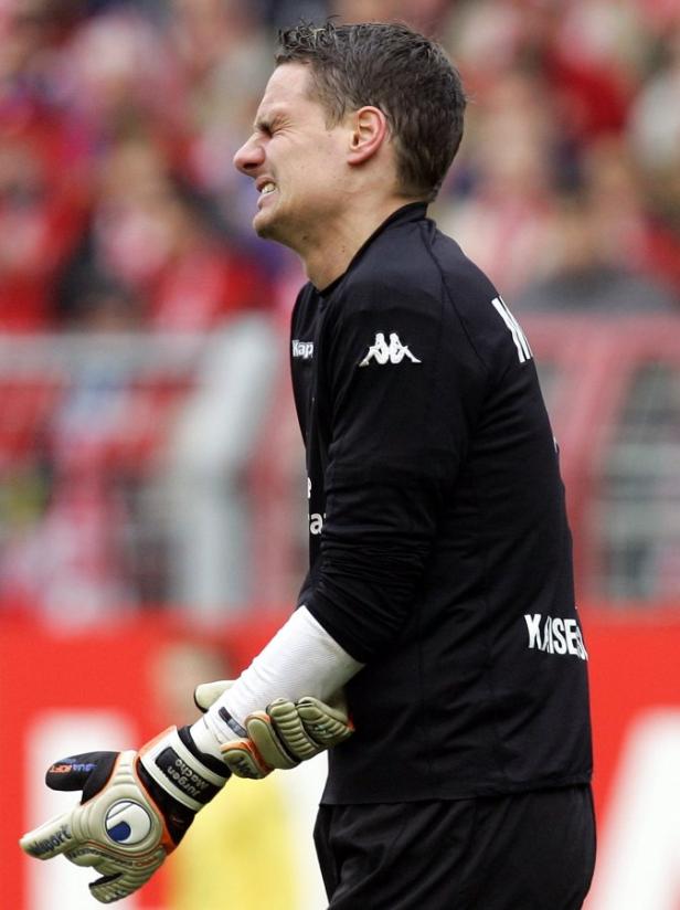 Ein Torwart in Sportkleidung mit schmerzverzerrtem Gesichtsausdruck.