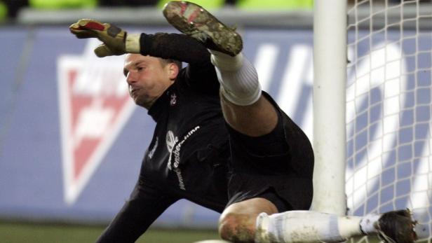 Ein Fußballtorwart wehrt einen Schuss mit dem Fuß ab.
