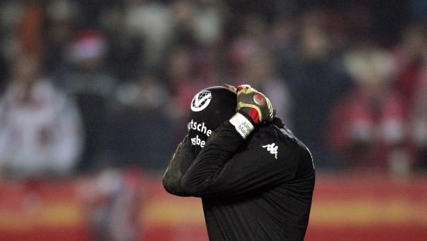 Ein enttäuschter Fußballtorwart mit dem Kopf in den Händen.