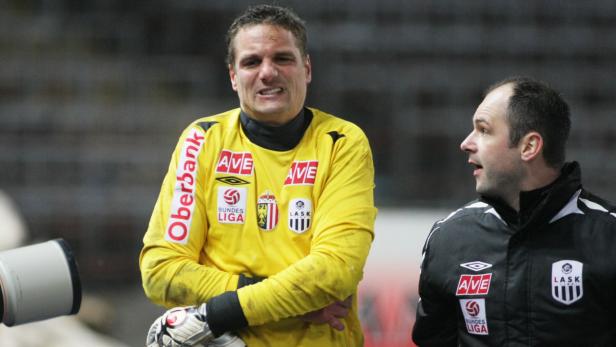 Ein Fußballtorwart in gelber Spielkleidung und ein Trainer an der Seitenlinie.