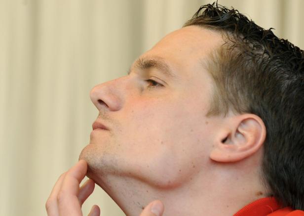 Ein Mann betrachtet sein Gesicht im Profil und berührt sein Kinn.