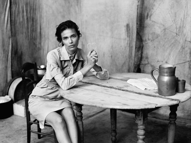 Eine Frau sitzt an einem Tisch und hält ein kleines Herz in der Hand.