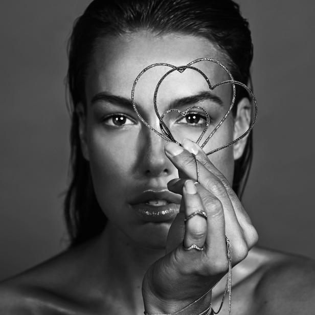 Eine Frau hält herzförmigen Schmuck vor ihr Auge.
