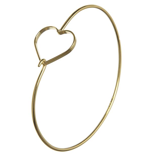 Ein goldener Armreif mit einem herzförmigen Detail.