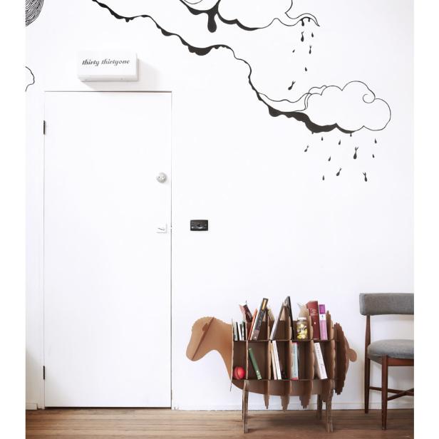 Ein Bücherregal in Form eines Schafs steht in einem Raum mit Wolken-Wandtattoos.