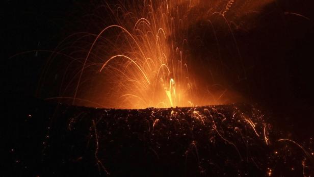 Ein Vulkan spuckt glühende Lava in einer dunklen Nacht.