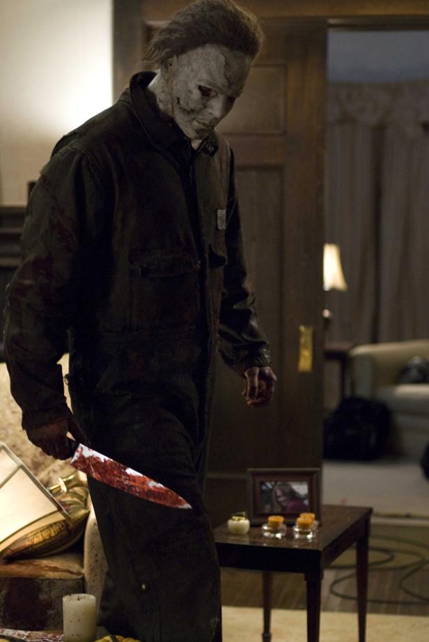 Michael Myers mit blutigem Messer in einem Wohnzimmer.