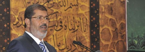Ägyptens Präsident Mursi verkündet die Neuigkeiten. Ein Mann mit Brille spricht vor einem Hintergrund mit arabischer Kalligrafie.