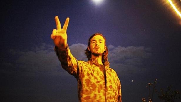 Ein Mann zeigt vor einem dunklen Himmel das Victory-Zeichen.