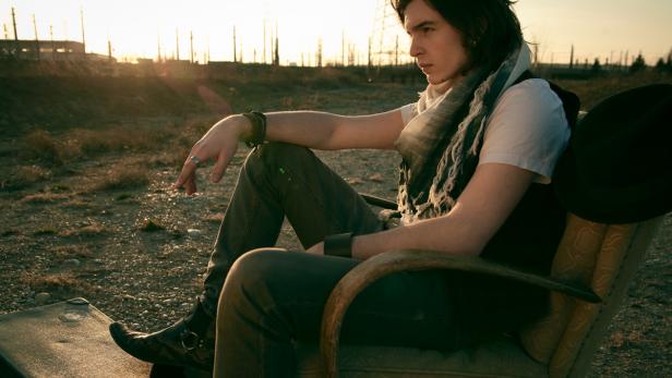 Ein Mann sitzt in einem Sessel im Freien, die Sonne scheint im Hintergrund.