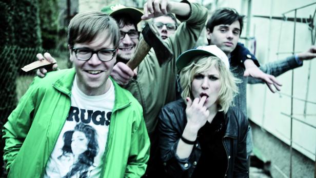 Eine Gruppe junger Leute posiert mit einer Axt und Holzstücken für ein Foto.