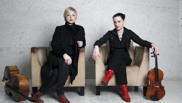 Zwei Frauen sitzen mit einer Geige und einem Cello in Sesseln.