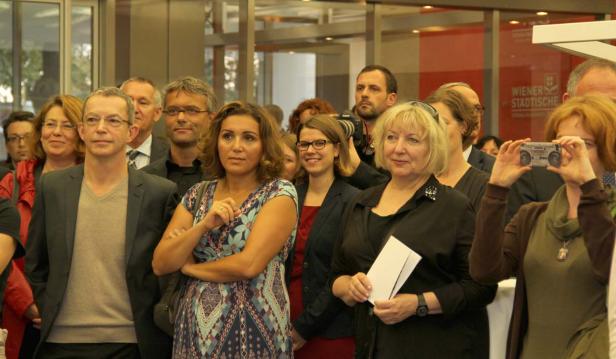 Eine Gruppe von Menschen steht in einem Raum und schaut in die gleiche Richtung.