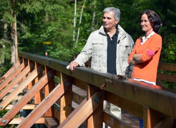 Ein Mann und eine Frau stehen auf einer Holzbrücke im Wald.
