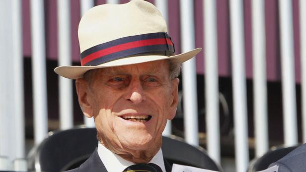 Prinz Philip mit einem hellen Hut mit blau-rotem Band.